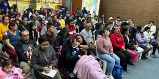 Foto de una comunidad diversa que se reúne en un espacio participativo, mientras familias y cuidadores escuchan y dialogan en torno a la discapacidad.