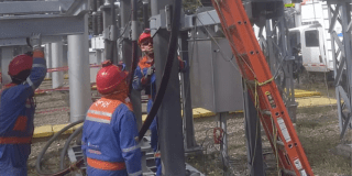 Imagen de tecnicos de Enel que revisan los cables de energía de un poste.