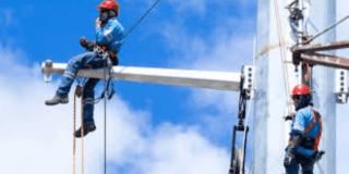 Imagen de tecnicos de Enel que revisan los cables de energía de un poste.