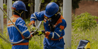 Imagen de técnicos de ENEL Codensa revisando unos cables junto a un poste de luz