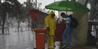 Imagen de dos personas escampando de la lluvia en Bogotá