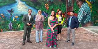 Imagen de varias personas al frente de un mural