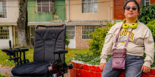 Imagen de una mujer en condición de discapacidad junto a una silla de ruedas