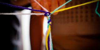 En la foto unas personas tejiendo redes de manera simbólica