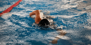 Imagen de un hombre jpoven nadando en una piscina.