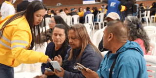 Imagen de una funcionaria de Integración Social atendiendo a diferentes personas