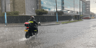 Imagen de un motociclista en una calle en el medio de una lluvia