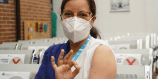 Imagan de mujer que ha sido vacunada indicando con su mano su aprobación.