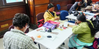 Imagen de varios artesanos trabajando sentados en una mesa