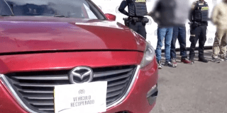 Imagen de un vehículo rojo y al lado hombres y agente de Policía de pie.