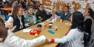 Imagen de varias personas tomándose de la mano alrededor de una mesa 