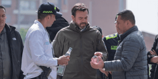 Imagen del alcalde Galán observando dos botellas de licor adulterado