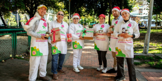 Imagen de varias personas posando para la foto alzando alimentos y con gorros de Navidad
