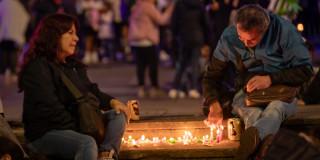 Foto que muestra dos personas sentadas en el piso prendiendo velas