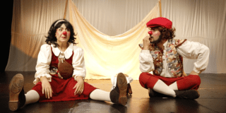 Imagen de dos payasos vestidos de rojo con blanco en escena.
