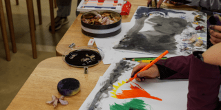 Imagen de varias personas sentadas en una mesa realizando actividades de artes plásticas.