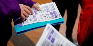 En la foto una seora mostrando un folleto con información sobre lo servicios de la Secretaría de la Mujer