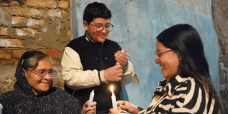 Foto de 3 personas prendiendo velas en Bogotá
