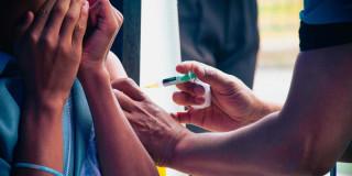 Foto que muestra una persona colocando una inyección en un brazo