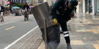 Foto que muestra una persona sacando basura de una caneca