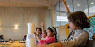Foto que muestra niños y niñas sentados en una sala 