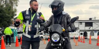 Foto de un hombre en una moto junto a un funcionario de Movilidad. 