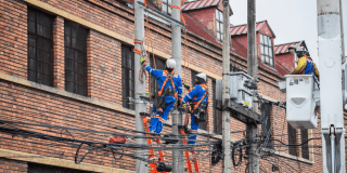 Imagen de técnicos de Enel colgados en postes de luz