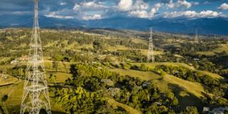La imagen muestra torres de transmisión de energía en un paisaje rural