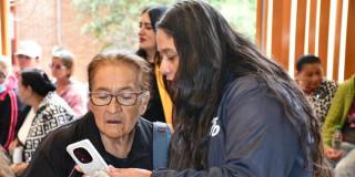 Funcionaria y mujer adulto mayor revisando información en el celular