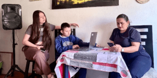 Imagen de una madre de familia con su hijo e hija estudiando en un computador
