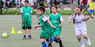 Foto de niños y niñas realizando prácticas deportivas en una cancha de fútbol.