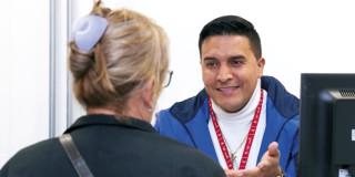 Foto de un funcionario del IPES entregando información sobre los cursos gratis de manipulación alimentos y formación para el trabajo.