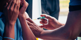 Foto de una enfermera colocando una vacuna en el hombro de una persona