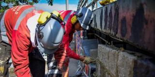 Trabajadores sellando huecos bajo el puente de la NQS con calle 19.