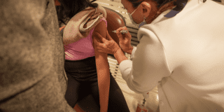 Foto de una enfermera colocando una vacuna en el hombro de una persona