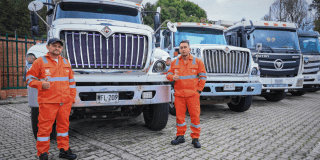 Imagen de dos operarios de aseo junto a camiones recolectores