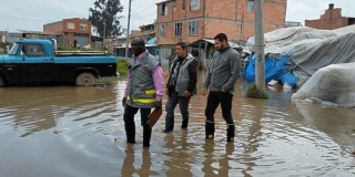 Imagen de tres personas caminando en un charco