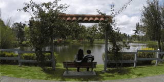 Imagen de una pareja de enamorados sentados en una banca a la orilla del lago en el Parque El Lago de Bogotá