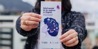 Mujer sosteniendo folleto de la Secretaría de la Mujer