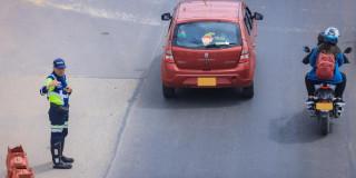 Foto que muestra un vehículo y una moto andando por una calle 