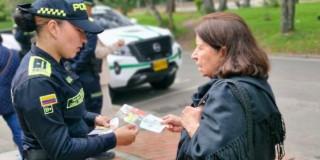 Uniformada de la Policía entregando información a ciudadana.