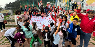 Imagen de varias personas alzando las manos pintadas de rojo
