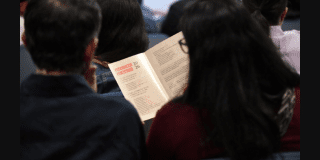 Imagen de un hombre y una mujer sentados leyendo un libro.