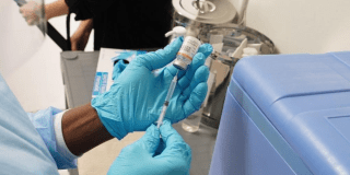 Foto que muestra una mano de una enfermera con una jeringa 