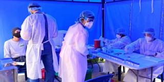 Foto que muestra un grupo de personas en una carpa con tapabocas