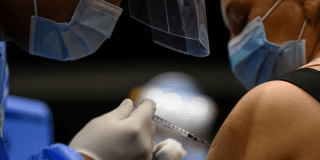 Foto de una enfermera colocando una vacuna en el hombro de una persona