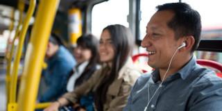 Foto de un hombre en un bus de TransMilenio usando audífonos.