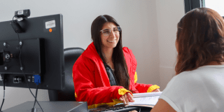 Imagen de una funcionaria atendiendo a una señora en una oficina