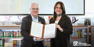 Foto que muestra dos personas sonriendo con un documento en las manos