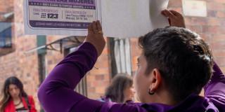 Mujer con un cartel sobre rutas de atención para mujeres víctimas de violencia.